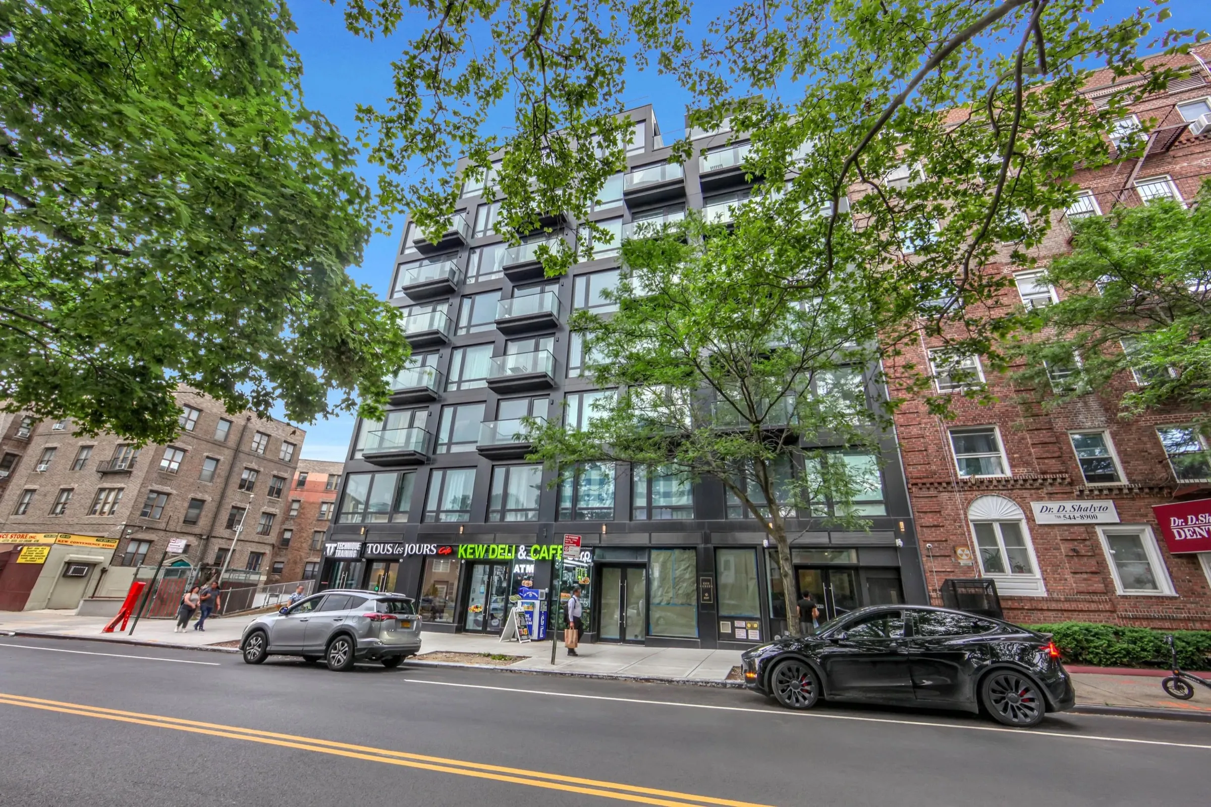 Photograph of the completed Evergarden — dark facade and glass balconies over tree-lined ground-floor retail